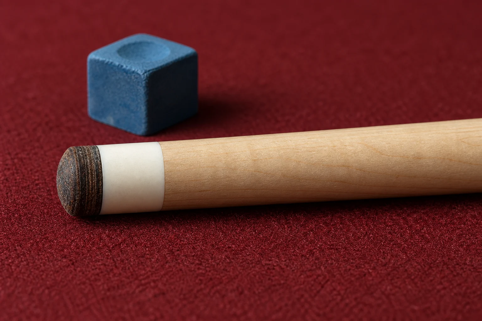 Layered leather pool cue tip, ferrule and blue chalk on burgundy cloth