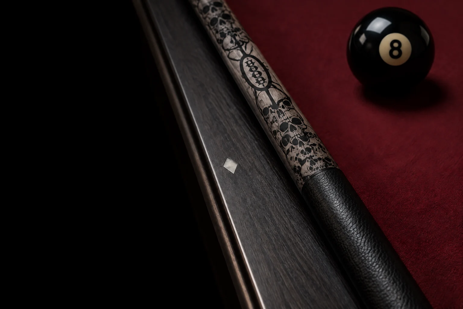Voodoo-inspired skull engraving and leather wrap beside an eight ball on burgundy cloth
